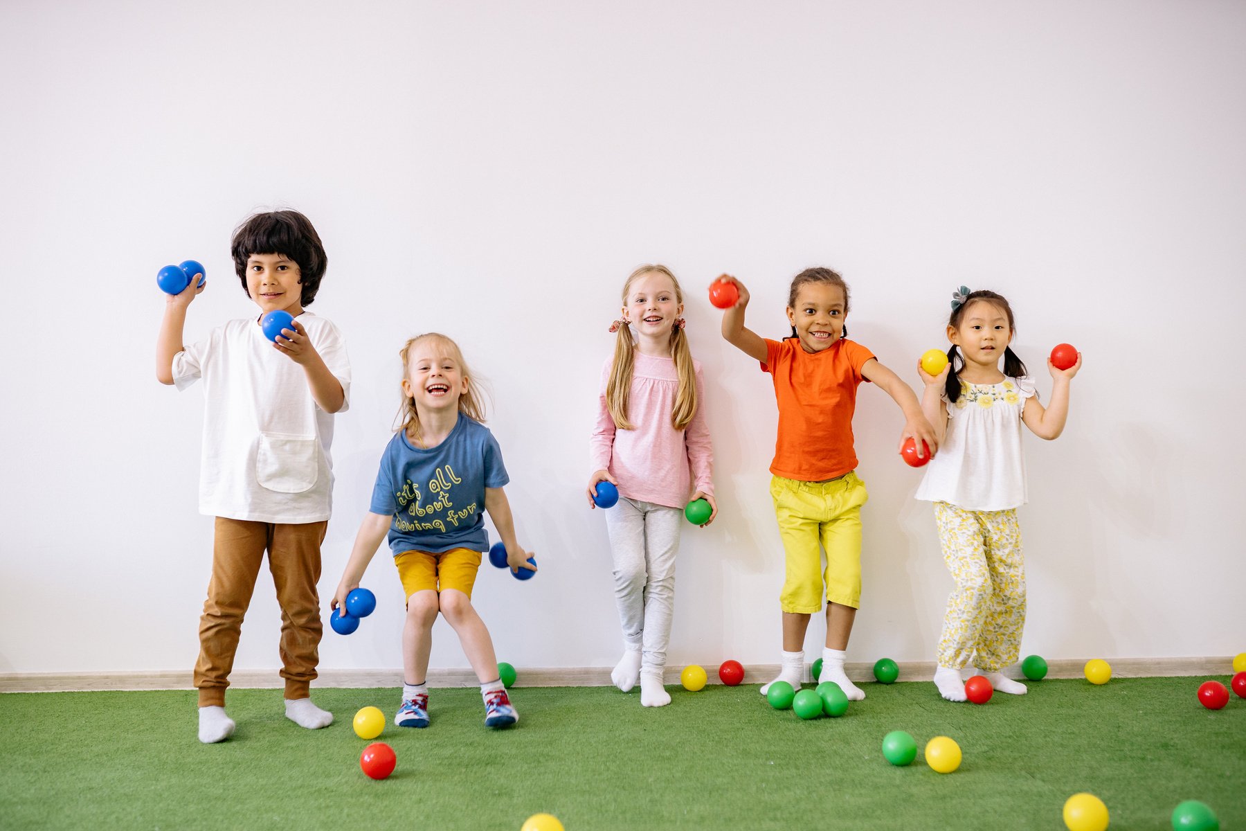 Little Girls and Boys Having Fun Playing With Colorful Balls